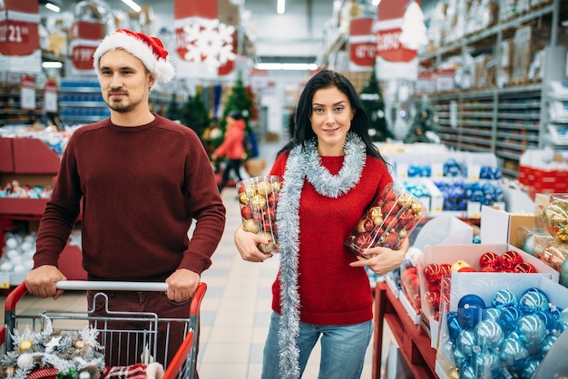 若いカップルが店でたくさんのクリスマスのおもちゃを選んだ