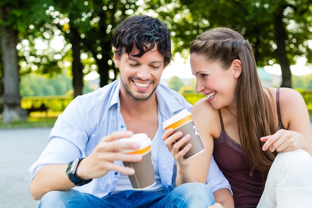 Young couple in city park drinking coffee