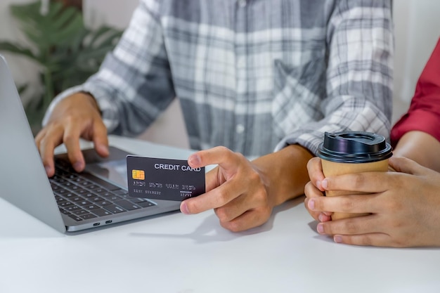 Foto giovane coppia di consumatori con in mano un modello di carta di credito pronta a spendere paga gli acquisti online in base