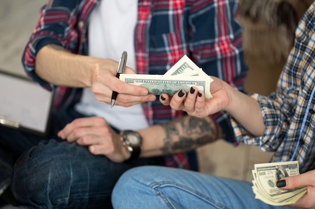 Young couple counting money while sitting on floor in new apartment