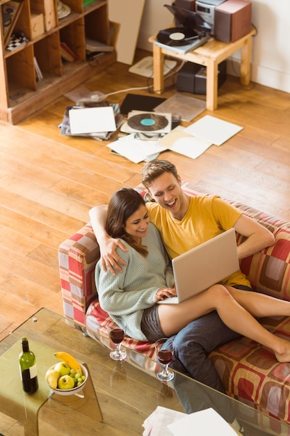 Young couple cuddling on the couch with laptop