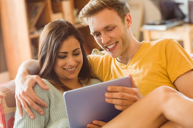 Young couple cuddling on the couch with tablet pc