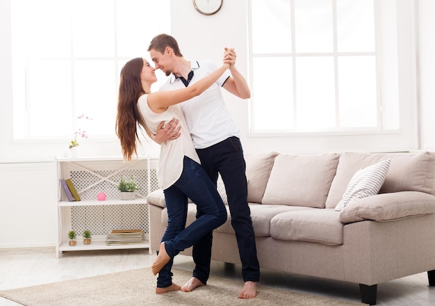 Young couple dancing at home, copy space. Romantic rest, man and woman having fun