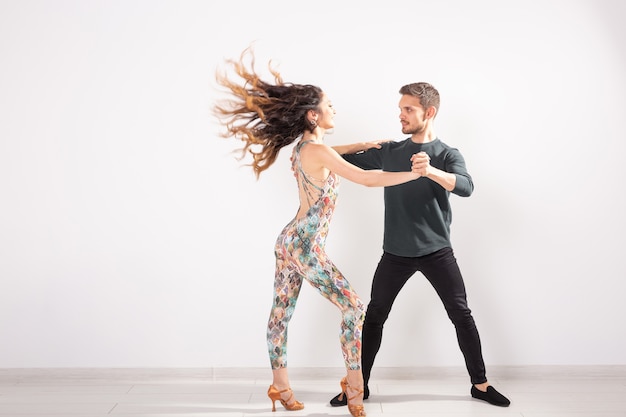 Young couple dancing latin dance bachata, merengue, salsa, kizomba. Two elegance pose over white background with copy space