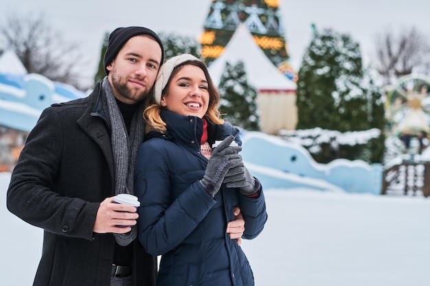 Young couple on a date near the ice rink, drinking coffee and talking