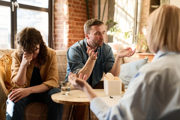 Young couple discussing their problems with psychologist during psycho session