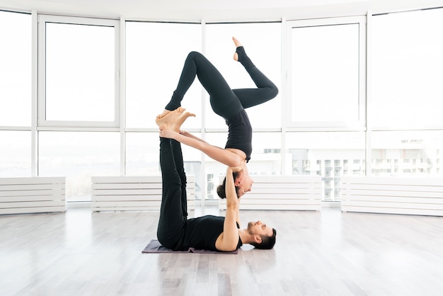 Young couple doing acro yoga in pair at studio