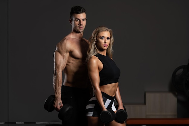 Young Couple Doing Exercise For Biceps With Dumbbells