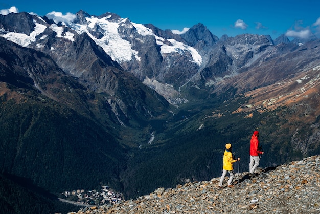 Young couple doing Nordic walking in the mountains, rear view. An active couple is engaged in Hiking. A young couple is engaged in tracking. Trekking and Nordic walking. Hiking. Dombay. Copy space