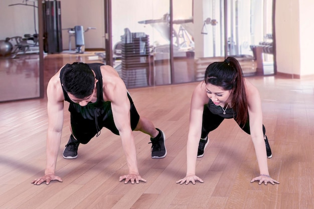 Young couple doing push up in fitness center