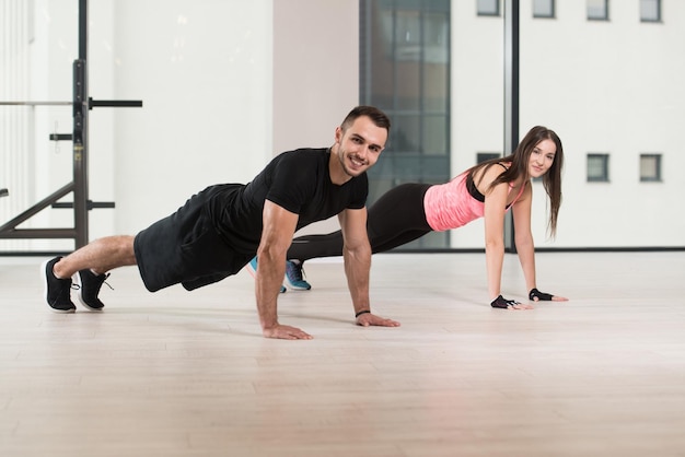 Giovani coppie che fanno esercizio di push-up in palestra