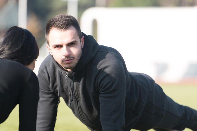 Foto coppia giovane facendo flessioni nell'area del parco cittadino formazione ed esercizio per il concetto di stile di vita sano di endurance fitness all'aperto