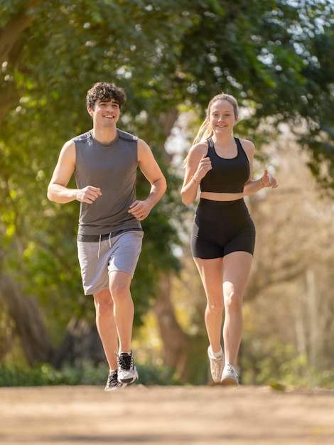 Young couple doing sports in the park They are running on a path between some trees