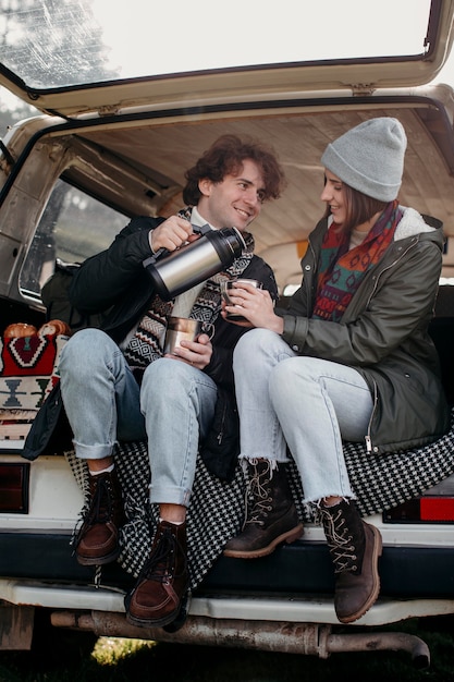 Young couple drinking coffee in a van