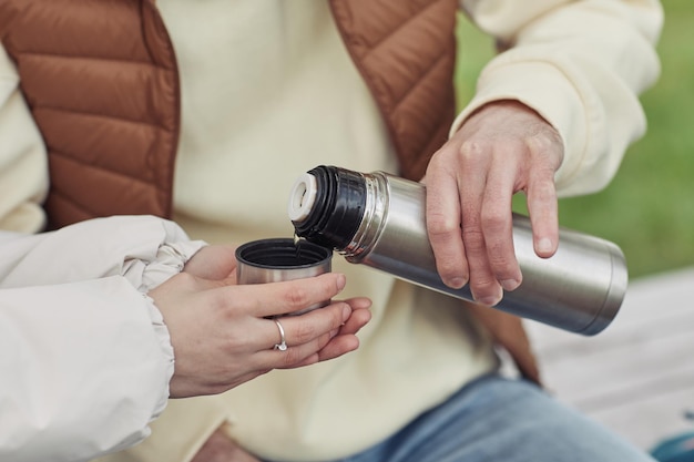 Young couple drinking hot tea from flask