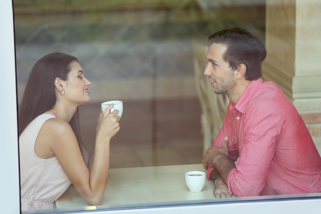 お茶を飲み、カフェで話す若いカップル