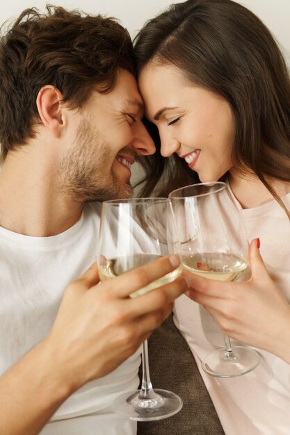 Молодая пара пьет белое вино и отдыхает дома