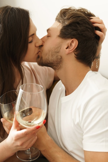 Молодая пара пьет белое вино и отдыхает дома