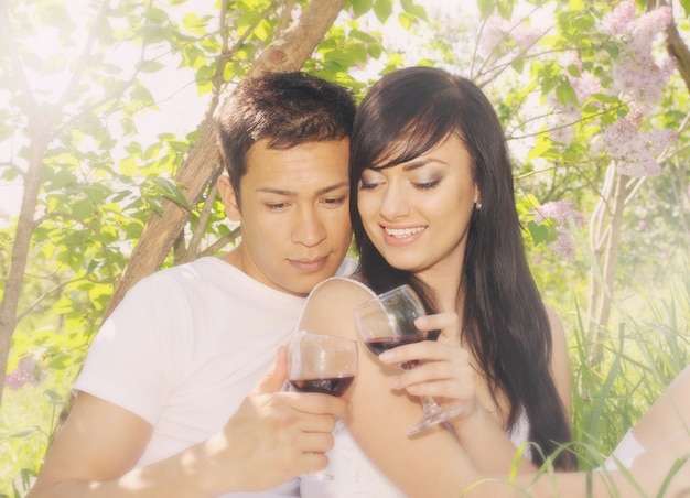 ライラックの茂みの下でワインを飲む若いカップル
