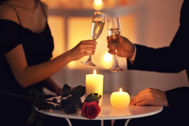 Photo young couple drinking wine while sitting at table with burning candles