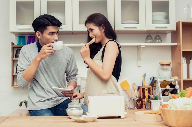 若いカップルが台所で朝食を食べる