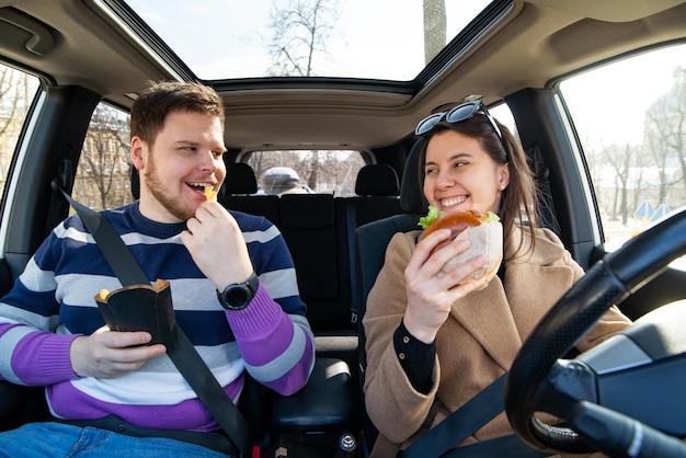 Young couple eating fast food in car