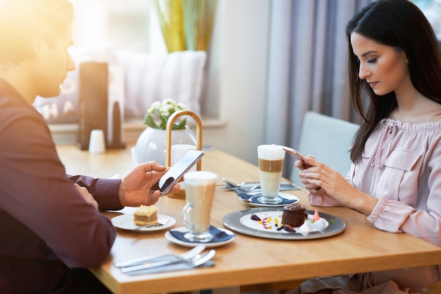 Photo young couple enjoying coffee and cake in cafe