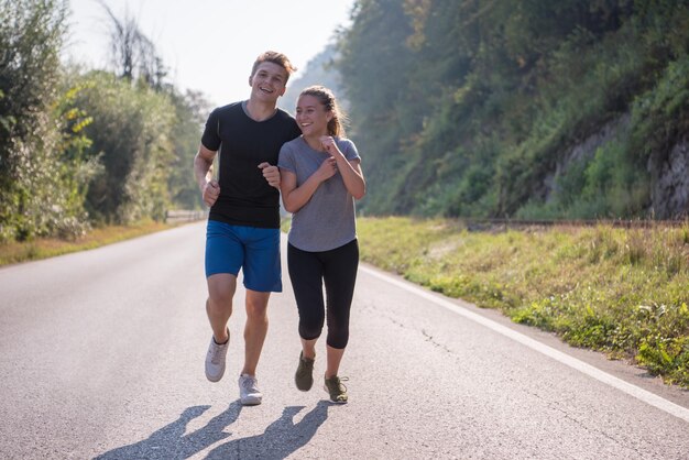 Foto giovane coppia che gode di uno stile di vita sano mentre fa jogging lungo una strada di campagna, esercizio fisico e concetto di fitness