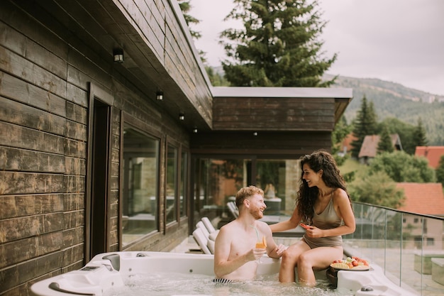 Young couple enjoying in outdoor hot tub on vacation