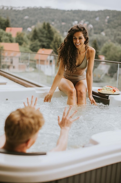 Young couple enjoying in outdoor hot tub on vacation