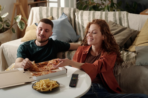 Young couple enjoying pizza and movie
