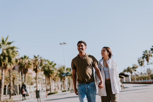 Photo young couple enjoying a sunny stroll along barcelona palmlined promenade