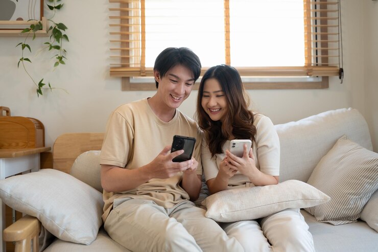 家のソファでスマートフォンと一緒に週末を楽しんでいる若いカップル