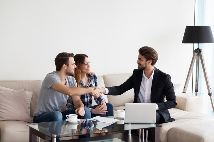 Photo young couple family at meeting with realtor interior designer decorator landlord making deal husband handshaking with man in suit concept of meeting with client customer