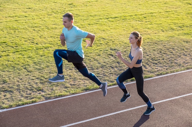 フィットスポーツマン男の子と女の子の運動をしながら実行しているの若いカップル