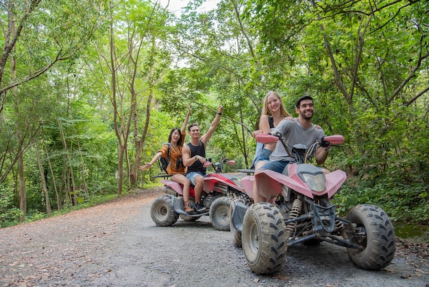 young couple or friend happy while riding an ATV in forest