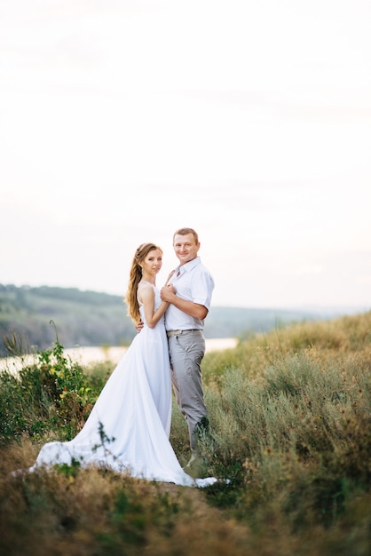 Young couple a girl and a guy are walking in the field against the background of the river