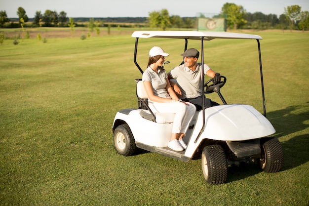 Foto giovane coppia al carrello da golf