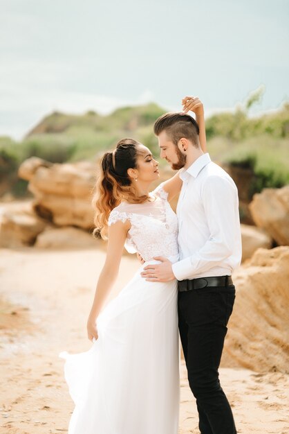 Young couple groom with the bride on a sandy beach at a wedding walk