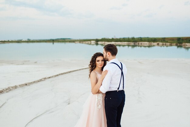 Young couple a guy in black breeches and a girl in a pink dress are walking along the white sand of the desert