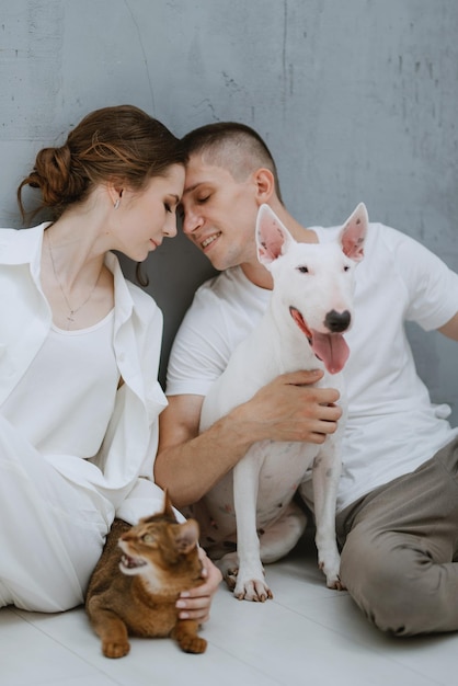 Foto coppia di ragazzi e ragazze in una stanza luminosa che giocano con gli animali domestici