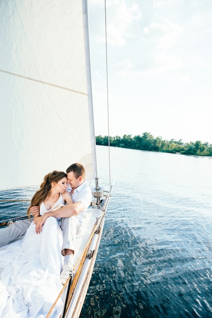 Young couple guy and girl on a white sailing yacht