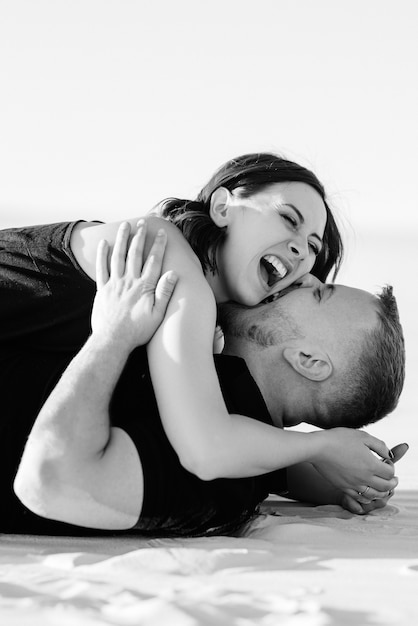 Young couple a guy and a girl with joyful emotions in black clothes walk through the snow white desert