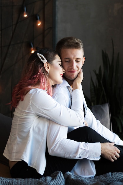 A young couple guy and a girl with pink hair passionately cuddle