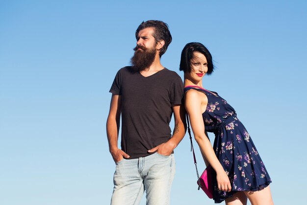 Young couple of handsome man bearded hipster and beautiful brunette woman pose on blue sky