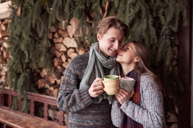 Young couple having breakfast in a romantic cabin outdoors in winter. Winter holiday and vacation. Christmas couple of happy man and woman drink hot wine. Couple in love