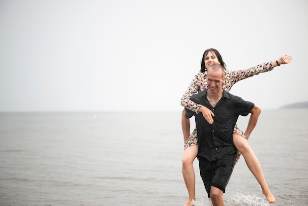 Photo young couple having fun on the beach at runny summer day