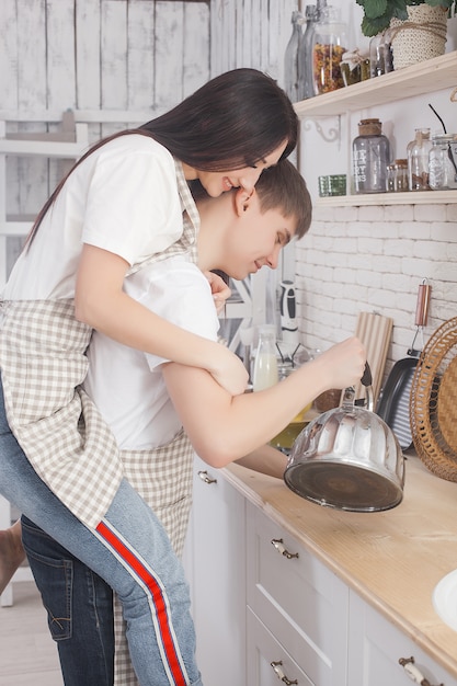 Young couple having fun at the kitchen. Attractive man and beautiful woman on kitchen background.