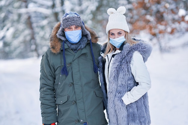 Young couple having fun on snow wearing mask. High quality photo