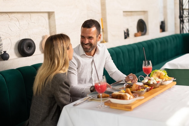 若いカップルがレストランで昼食を食べ新鮮なジュースを飲んでいます